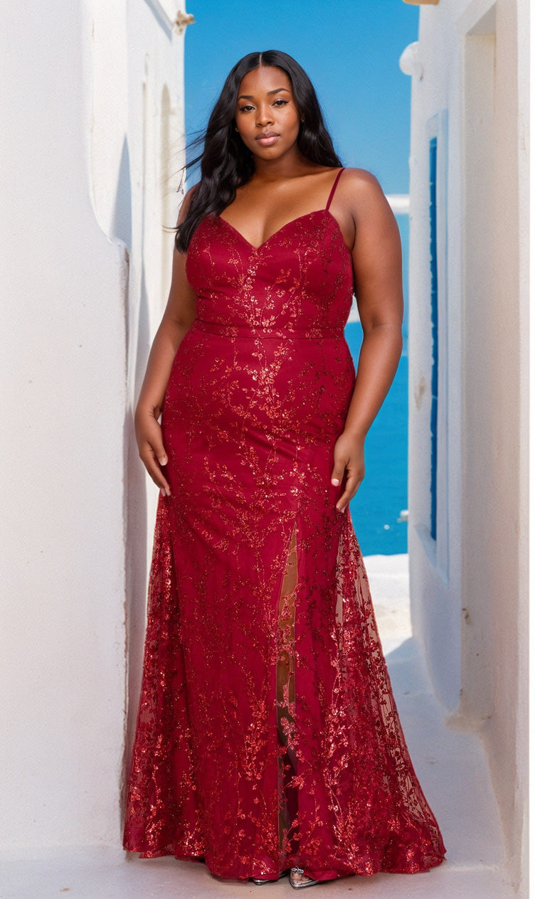 A woman in the Glitter Plus-Size Long Mermaid Prom Dress W1154, a sleeveless red gown with thin straps, stands outdoors between white buildings, with blue sky and sea in the background.